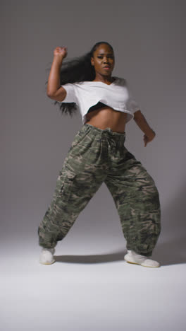 Vertical-Video-Full-Length-Studio-Portrait-Shot-Of-Young-Woman-Dancer-Dancing-In-Against-Grey-Background-In-Slow-Motion